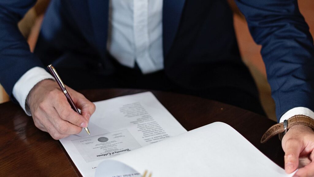 Persona revisando y firmando un documento de presupuesto sobre una mesa