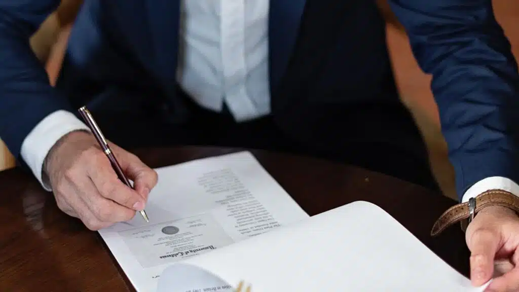 Persona revisando y firmando un documento de presupuesto sobre una mesa