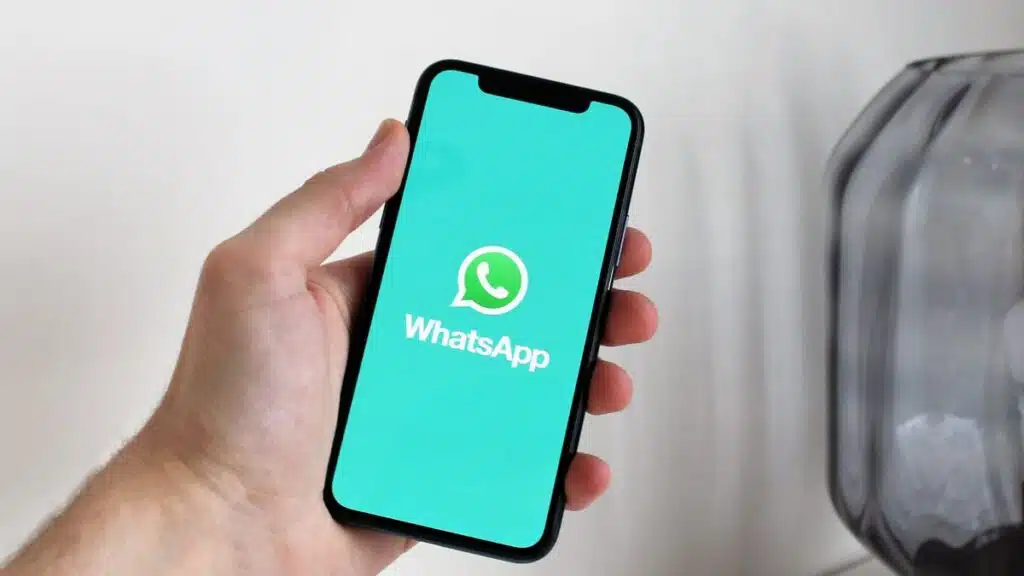 Mano sosteniendo un móvil con WhatsApp abierto, atención al cliente automatizada con IA
